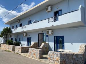 a white building with blue doors and a stone wall at Blue Sky in Frangokastello