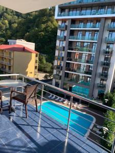 ein Balkon mit Tisch und Stühlen und ein Pool in der Unterkunft Hotel Neptun Kvariati in Kwariati