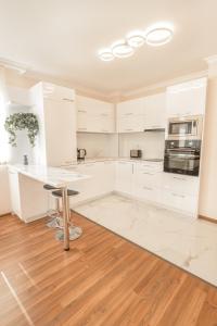 a kitchen with white cabinets and a wooden floor at Etica Apartments in Plovdiv