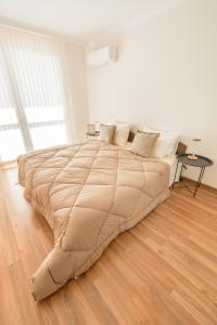 a large bed in a white room with a wooden floor at Etica Apartments in Plovdiv