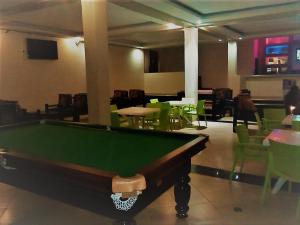 a pool table in a room with green tables and chairs at The Adrace Exec. Hotel in Kampala