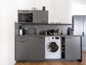 eine Küche mit einer Waschmaschine und einer Mikrowelle in der Unterkunft limehome Erfurt Schmidtstedter Straße in Erfurt