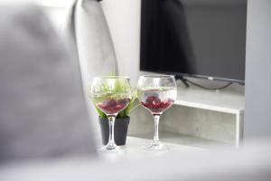 two wine glasses sitting on a table next to a tv at Your Sheffield Stays - Spacious 5 Bedroom House in Sheffield