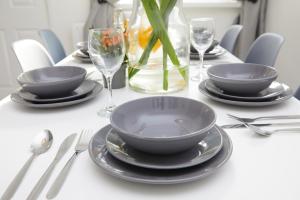 a table with plates and glasses and a vase with a plant at Your Sheffield Stays - Spacious 5 Bedroom House in Sheffield