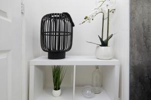 a black and white vase on a white shelf with plants at Your Sheffield Stays - Spacious 5 Bedroom House in Sheffield