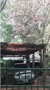 a car parked under a canopy with pink flowers at Jardín de Naipí 3 in Puerto Iguazú