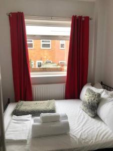 a bedroom with a bed with red curtains and a window at Chester Le Street Amythyst 3 Bedroom House in Chester-le-Street