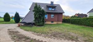 a house with a tree in the yard at Querenhorst, Unterkunft am Feld in Querenhorst