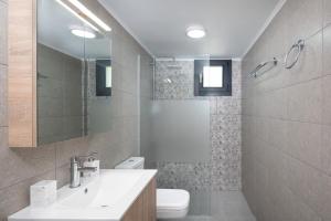 łazienka z umywalką, toaletą i lustrem w obiekcie Capostango Apartments - Stunning Views of Libyan Sea w mieście Áno Rodhákinon +33 zdjęcia