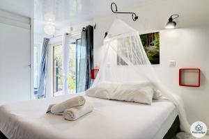 a white bedroom with a bed with a window at Le Bambou - 2 étoiles - Les Avirons in Les Avirons