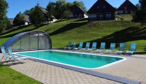 a swimming pool with chairs and an arch over it at Relax Chalet in Cerny Dul