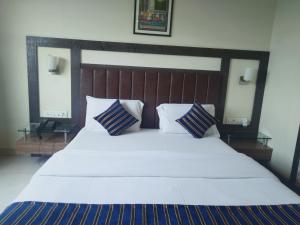 a large bed with white sheets and blue pillows at Hotel Udayanraje Palace in Ahmadnagar