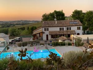 una villa con piscina di fronte a una casa di Naturaverde Country House a Senigallia