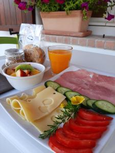 a plate of food with meats and cheese and a drink at Naturaverde Country House in Senigallia