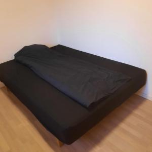 a black bed in a room with a white wall at Agervej 45, Borris in Skjern