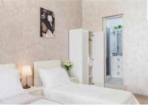 una camera da letto bianca con due letti e uno specchio di Rome Place a Roma