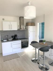 a kitchen with white cabinets and a table with chairs at Cabourg - Bel appartement lumineux avec balcon dans résidence privée in Cabourg