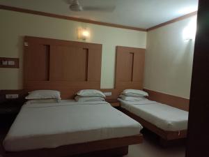 two beds in a small room with at Hotel A P in Coimbatore