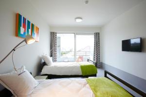 a bedroom with two beds and a tv and a window at Hotel Middelpunt - Gratis Parking - Ontbijt inbegrepen - in Middelkerke