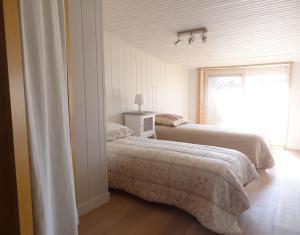 two beds in a white room with a window at LA SUITE GRANDE MAISON AU COEUR DU VILLAGE DE LA FLOTTE EN RÉ in La Flotte