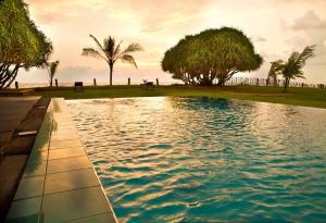 a swimming pool with palm trees in the background at The Pleasure Kosgoda in Bentota