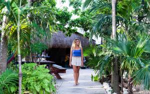 a woman walking down a path through a resort with palm trees at Hostel Oryx Tulum in Tulum