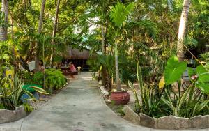 a path through a garden with palm trees and people sitting on benches at Hostel Oryx Tulum in Tulum