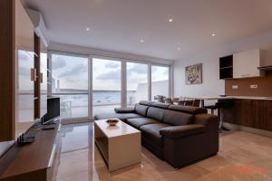 a living room with a leather couch and a table at Seafront Penthouse w unobstructed Sea Views in Mellieħa