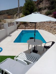 una mesa con sombrilla junto a la piscina en Almond Reef Casa Rural en Los Alias