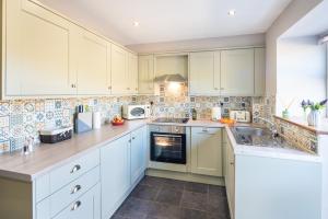 a kitchen with white cabinets and a sink at Coeden Afal in Kidwelly