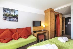 a hotel room with two beds and a television at Hôtel Les Menuires Les Bruyères in Les Menuires