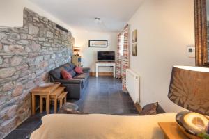 a living room with a stone wall and a couch at Wrth y Nant in Saint Ishmael