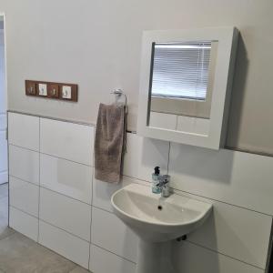 Un baño blanco con lavabo y espejo. en Clarens Escape (Unit 2), en Clarens 12 fotos más