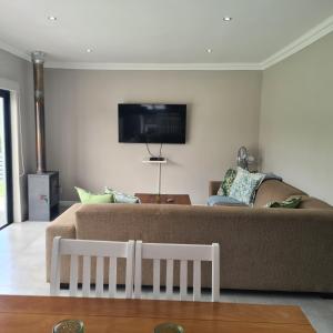Una sala de estar con un sofá y un televisor en la pared. en Clarens Escape (Unit 2), en Clarens