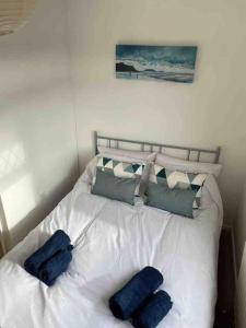 a white bed with blue pillows on top of it at Cosy coastal home - 5 mins walk from the beach in Horton
