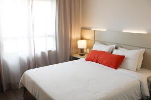 een slaapkamer met een groot wit bed met een rood kussen bij Samba Tres Rios in Três Rios