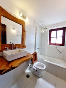 een badkamer met een wastafel, een toilet en een spiegel bij Hotel La Cumbrecita in La Cumbrecita