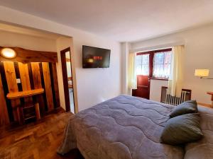 um quarto com uma cama e uma televisão na parede em Hotel La Cumbrecita em La Cumbrecita