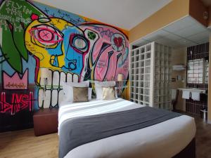 a bedroom with a bed and a wall covered in graffiti at The Originals Boutique, Hôtel de l'Univers, Montluçon in Montluçon