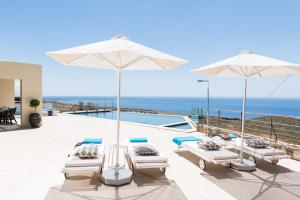 un patio con sillas y sombrillas y el océano en Villa Thetis Sfakia, en Sfakiá