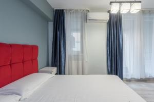 1 dormitorio con cama blanca y cabecero rojo en Downtown Accommodation, en Bucarest