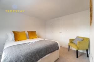 een slaapkamer met een bed en een gele stoel bij HIGH SPEC MODERN APARTMENT PRIME LOCATION! PARKING in Reading