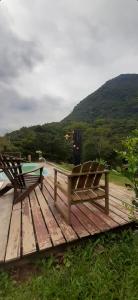 a wooden deck with two benches and a table at Serra Mar à beira rio , rafting, suites, lofts, e Casas in Casimiro de Abreu