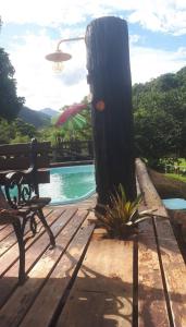a bench sitting next to a swimming pool with at Serra Mar à beira rio , rafting, suites, lofts, e Casas in Casimiro de Abreu