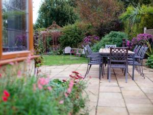 a patio with a table and chairs in a garden at Kingfisher Cottage in Winchcombe