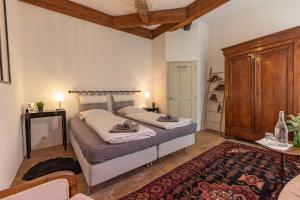 a bedroom with two beds and a wooden cabinet at Les Chambres du Lavoir Vert in Tourbes +49 photos