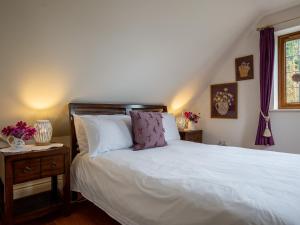 a bedroom with a bed with white sheets and a window at Kingfisher Cottage in Winchcombe