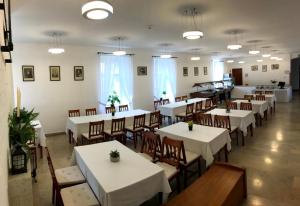un comedor con mesas y sillas blancas en Huszárvár Hotel Kastélyszálló, en Szerencs