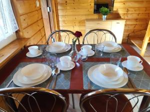 - une table à manger avec des assiettes, des bols et des chaises dans l'établissement Domki u Reksa, à Dębki