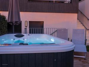 a jacuzzi tub with a chair and an umbrella at Résidence Les Suites Du Ferret in Cap-Ferret